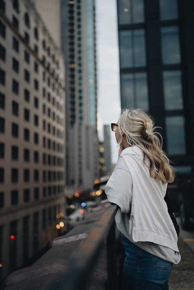 a girl admiring the city with a white top and jeans. 