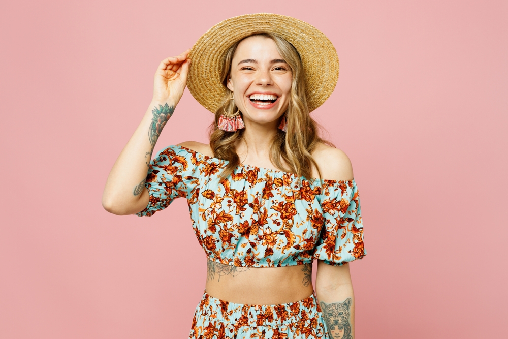 women in summer outfit with blue top and hat on oink background. 