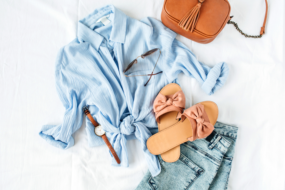 blue blouse with shorts, sandals that have bows on them, and a crossbody bag 