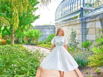 a girl in white dress walking in botanical garden