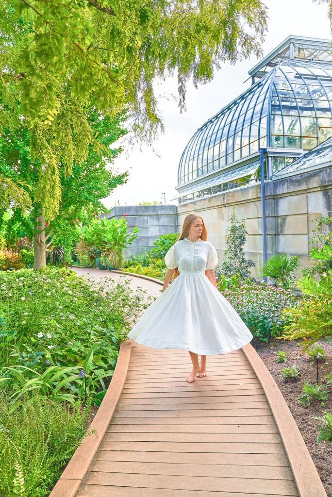 an outift idea for those looking at what to wear in Washington Dc in summer, girl in white dress walks on wooden boardwalk in botanical garden