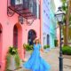 woman standing in a blue dress in Charleston in front of cute colored buildings