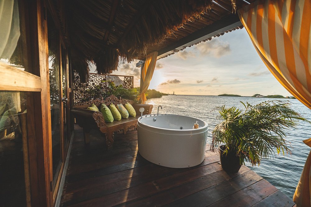 Wonderful interior of a water bungalow showing a sofa and a bath overlooking water. 