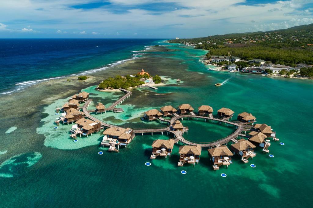 overwater bungalows leading from an island. They are in a heart shape.  