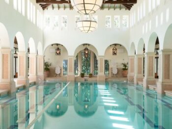 interior pool with arches and white walls with light coming in and making small squares on the water