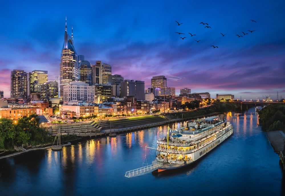 Nashville, which is one of the cheapest places to fly from Atlanta, comes alive at night as the sky turns purple and blue and the lights of the city turn on: birds fly overhead, and guests gather on a boat on the river.