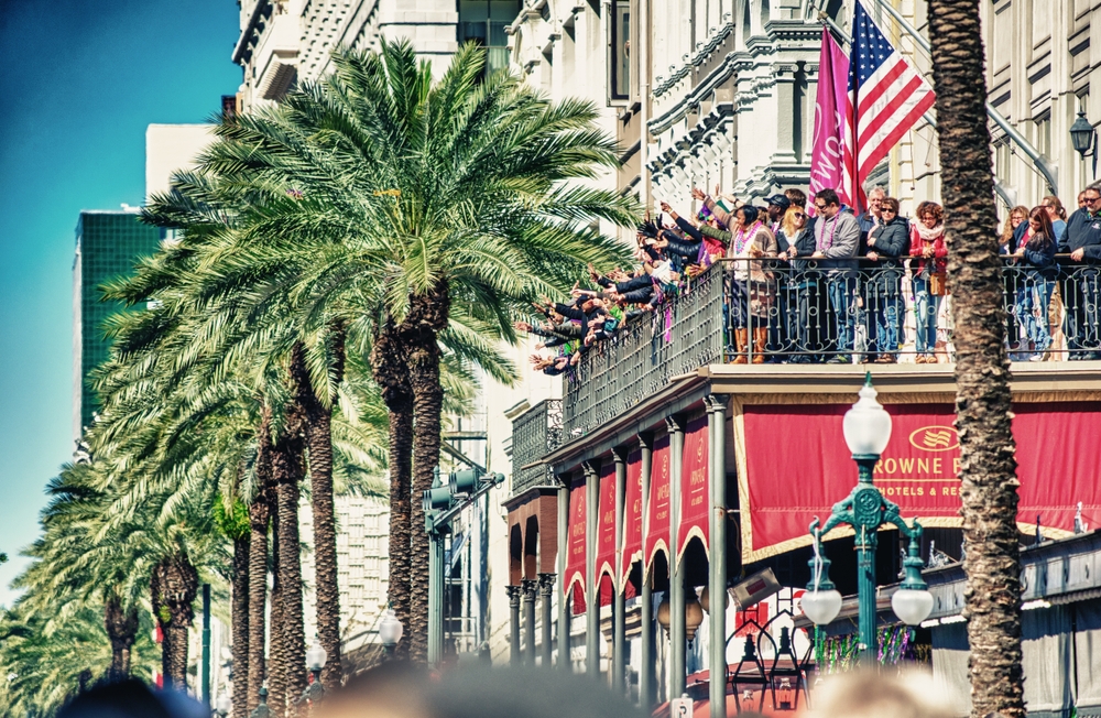 Groups of people stand on a balcony ready for a festival in NOLA.