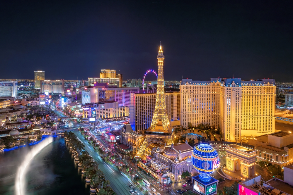 An overhead shot of Vegas shows the strip at night, bright lights and themed with entertainment and attractions.
