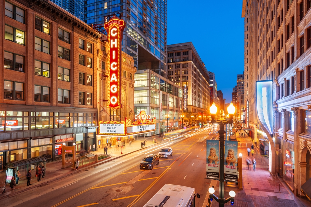 A street in Chicago is lit up at night with street signs a glow as cars travel south.