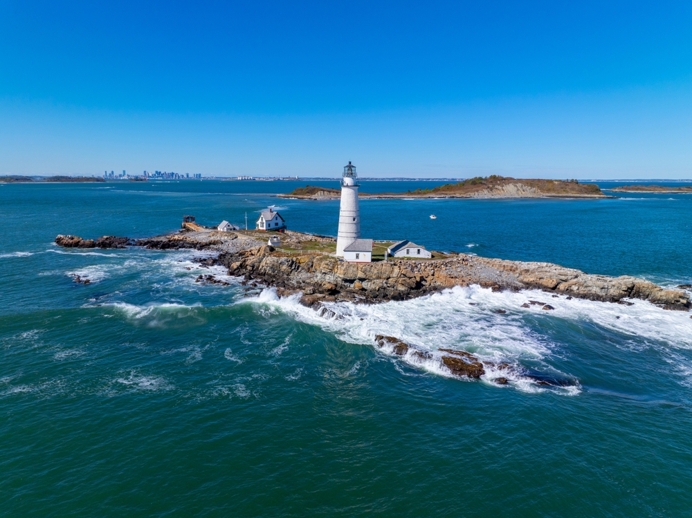 A lone lighthouse stands tall against the crashing waves on a island off the cusp of Boston, Mass. 