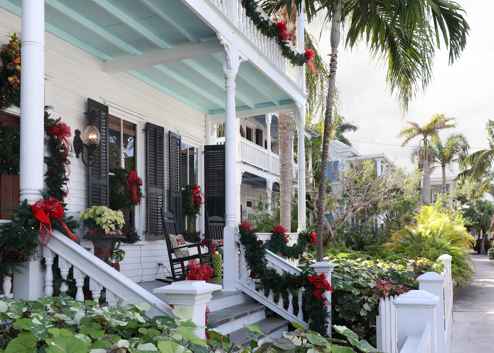 Key West style home during the holidays decorated for Christmas with Palm Trees in the landscape. The article is about Christmas in the South USA. 
