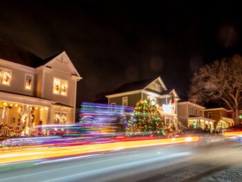 Outdoor christmas decorations on a street at night. there is a blur from the camera for some of the lights and some you can see in focus such as christmas trees