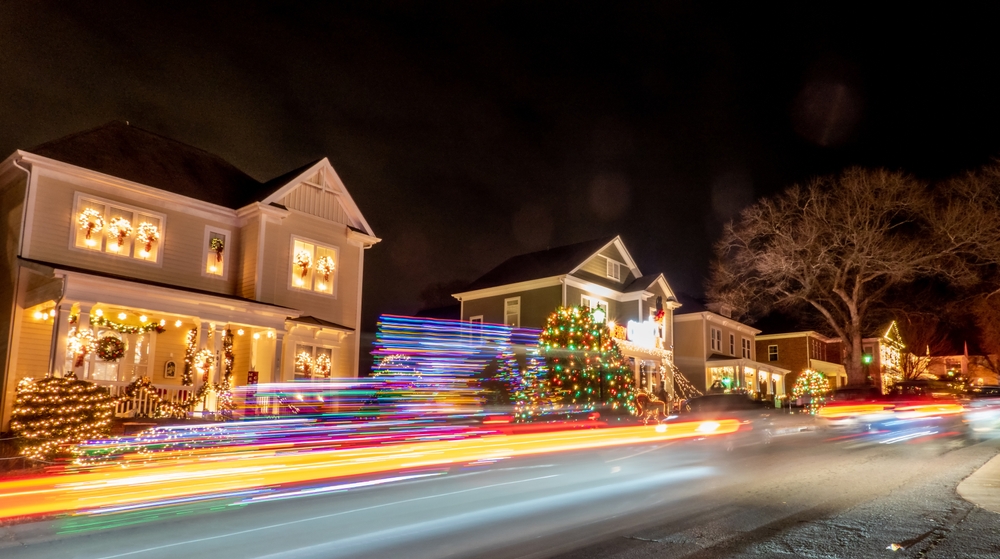 Outdoor christmas decorations on a street at night. there is a blur from the camera for some of the lights and some you can see in focus such as christmas trees