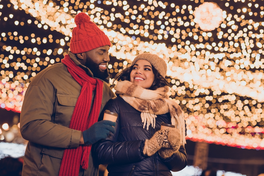A couple in front of holiday lights.