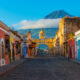 Cityscape of the main street and yellow Santa Catalina arch in the historic city center of Antigua at sunrise with the Agua volcano, Guatemala.
