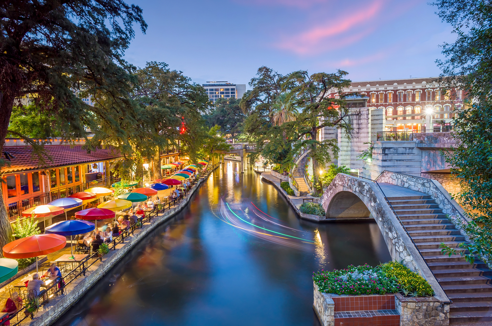 River walk in San Antonio city downtown skyline cityscape of Texas USA at sunset. This article is about cheapest places to fly from Nashville.